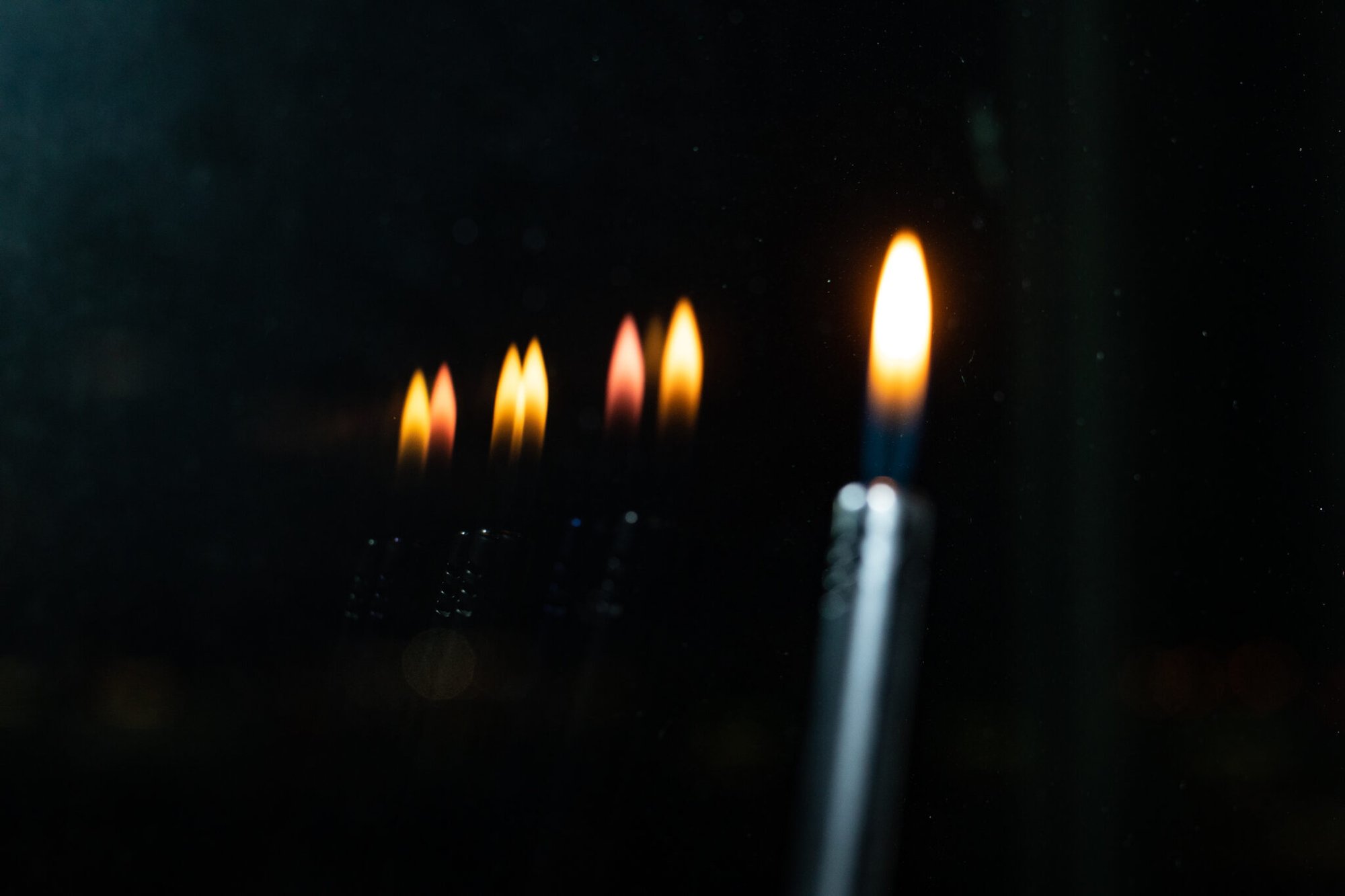 Tända ljus reflekteras i mörkt fönsterglas.