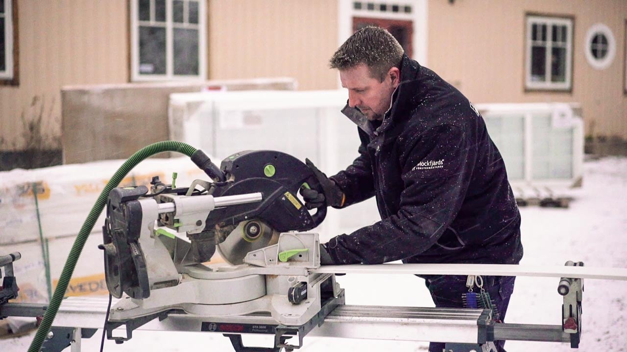 Hantverkare kapar material med kapmaskin utomhus i vintermiljö.