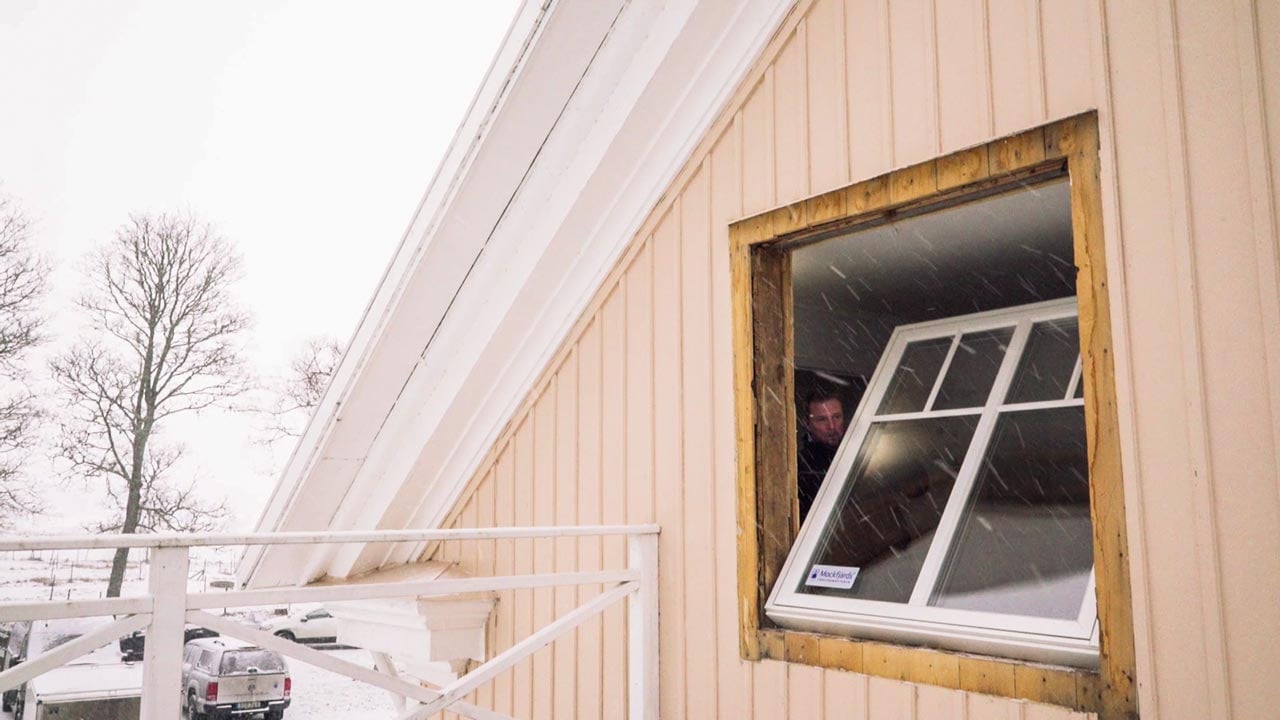 Montör lyfter in nytt fönster i husfasad under installation.