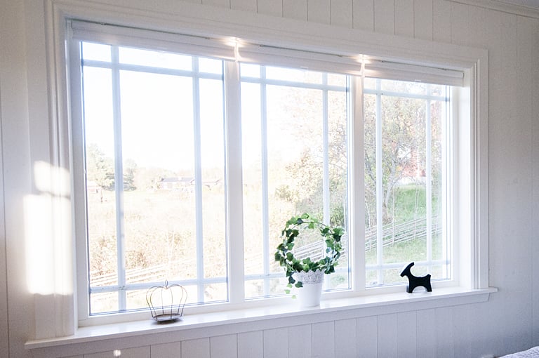 Stort fönsterparti med spröjs och dekorationer i fönsterkarm.