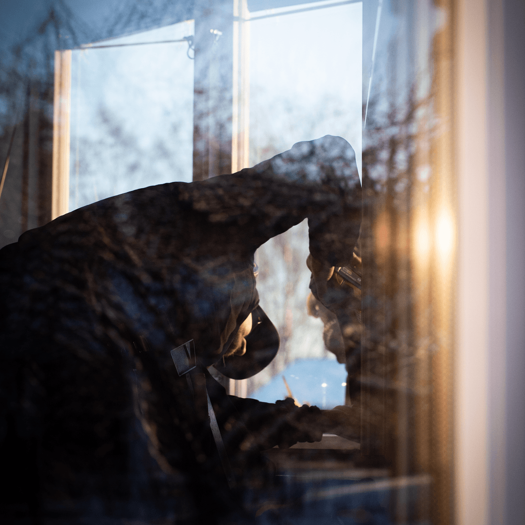 Person installerar ett fönster medan kvällsljus speglas i glaset.