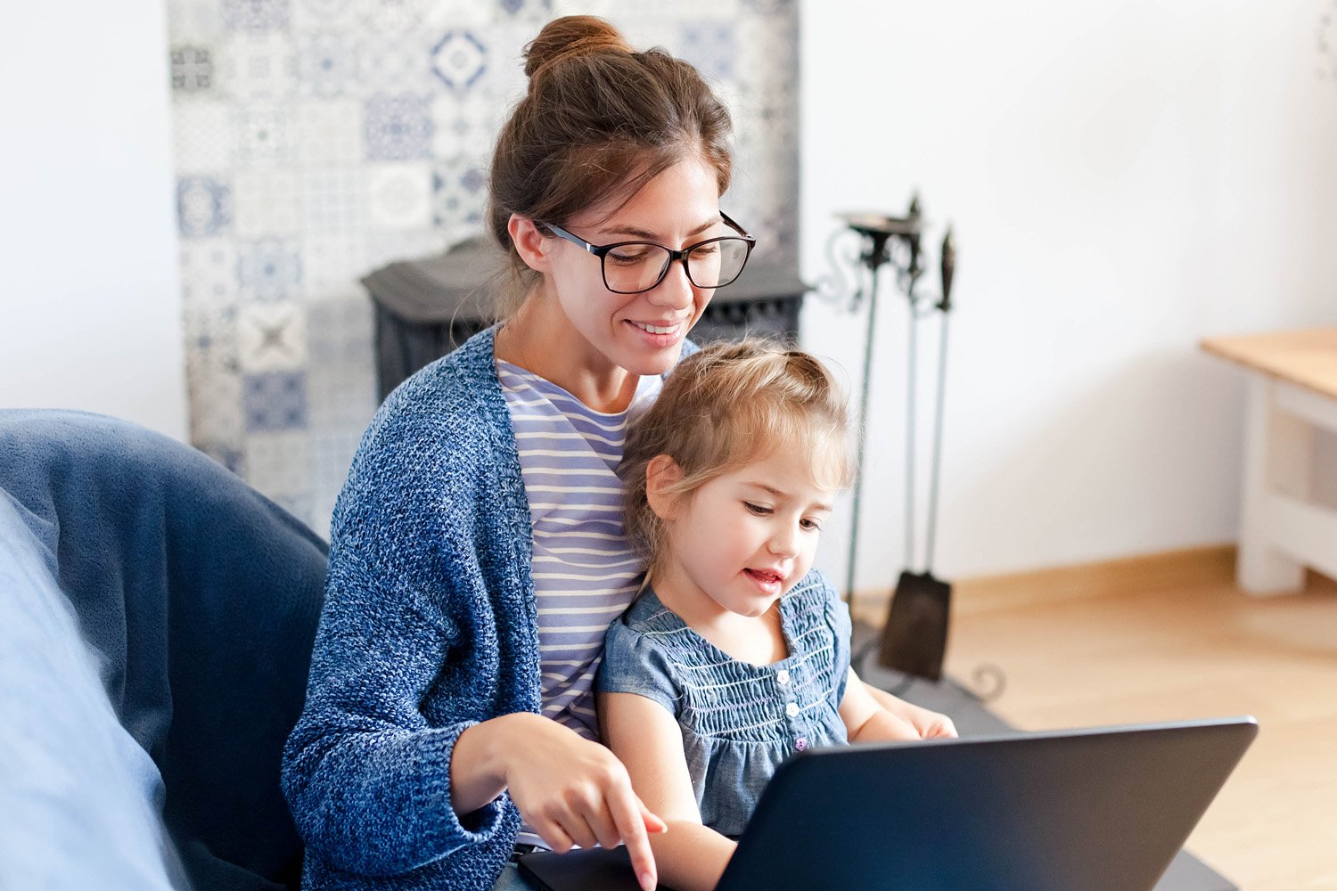 Förälder och barn sitter tillsammans i soffan och använder en laptop.