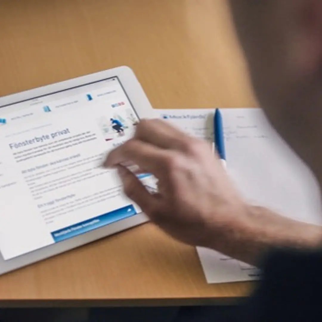 Person fyller i formulär på surfplatta för att få pris på fönsterbyte.