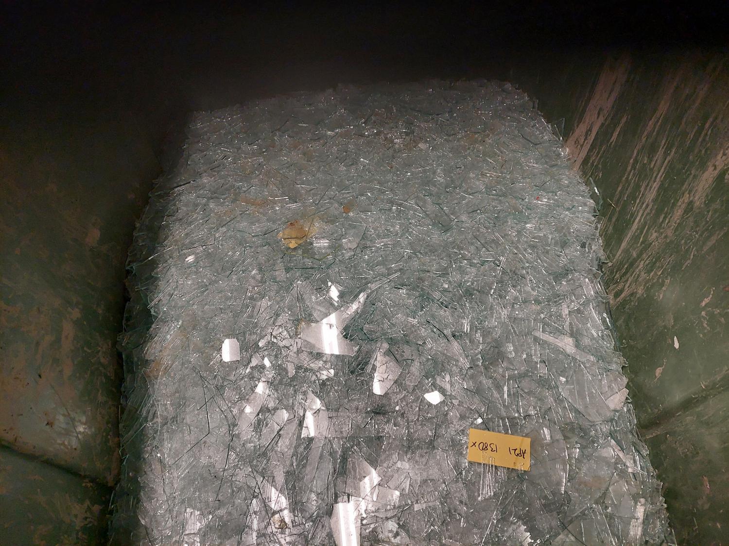 Container fylld med krossat glas för återvinning.