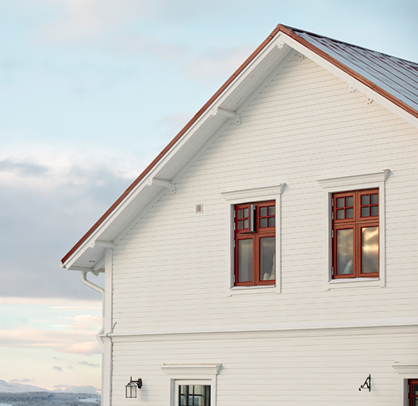 Vit villa med röda fönsterkarmar och klassisk arkitektur.