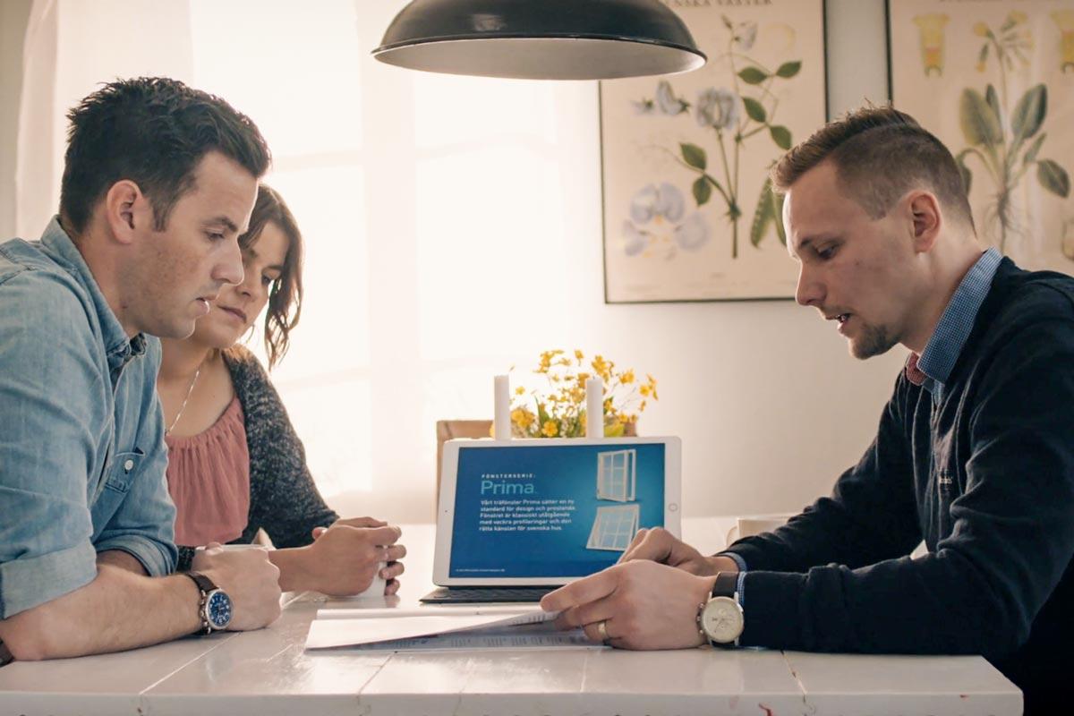 Rådgivningsmöte där kundpar får information om fönster vid köksbord.