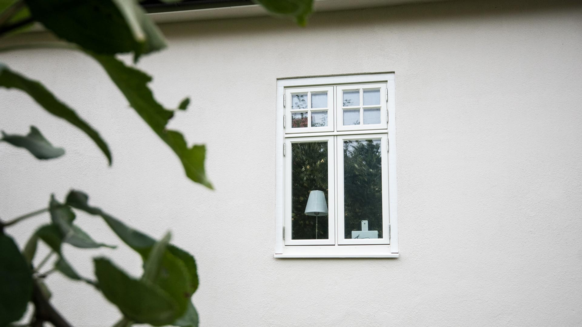 Fönster i vit fasad med insyn till inredning.