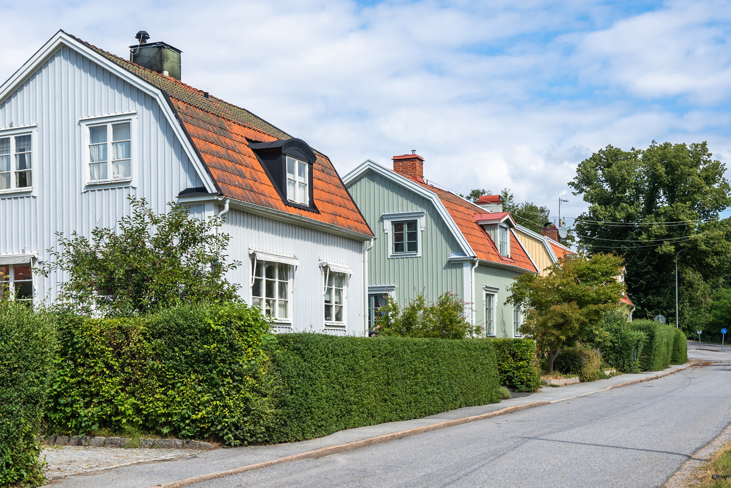 Rad av färgglada villor med fönster längs lugn gata.